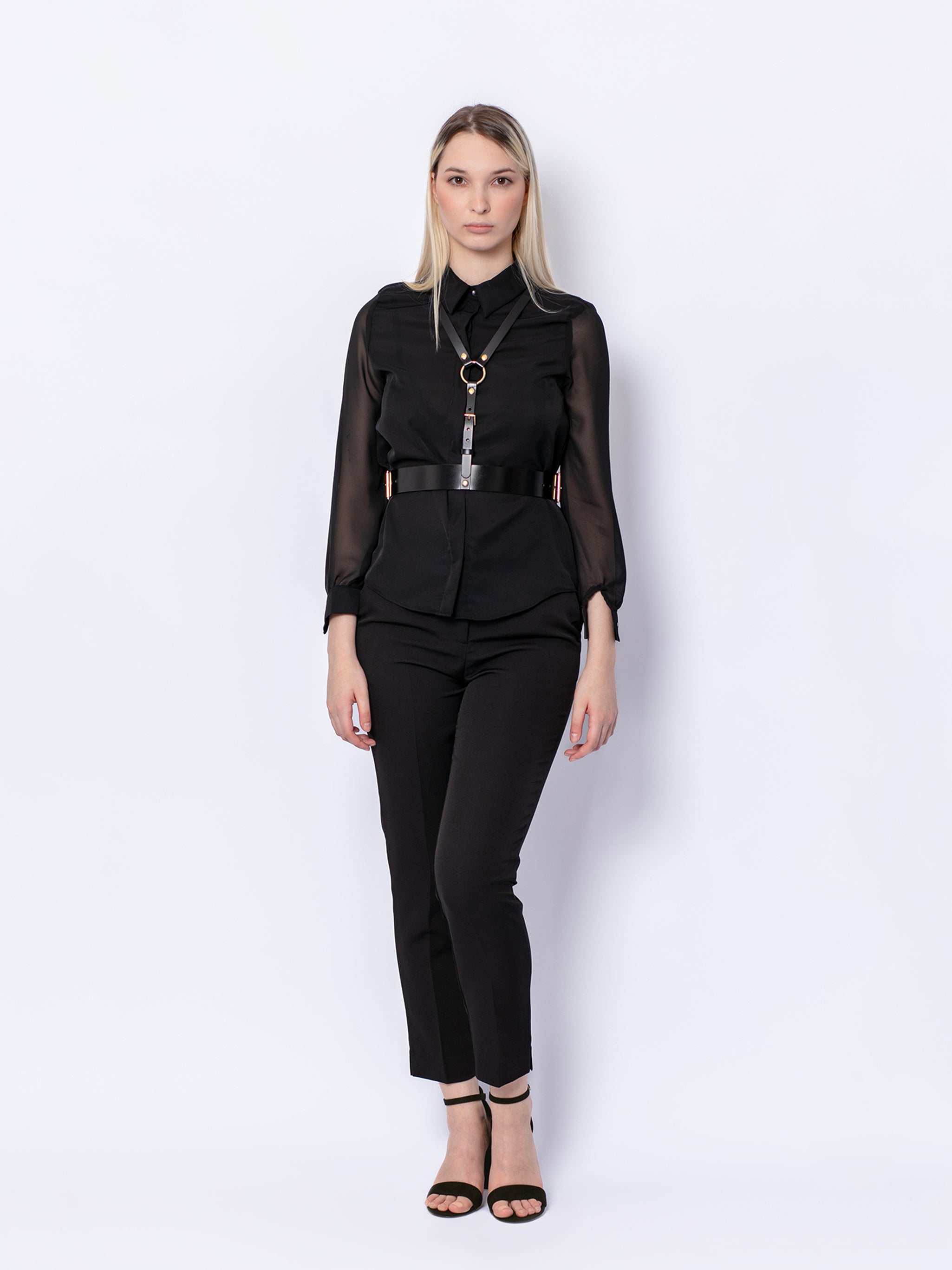 Front view of black leather harness worn by model over black shirt and trousers.