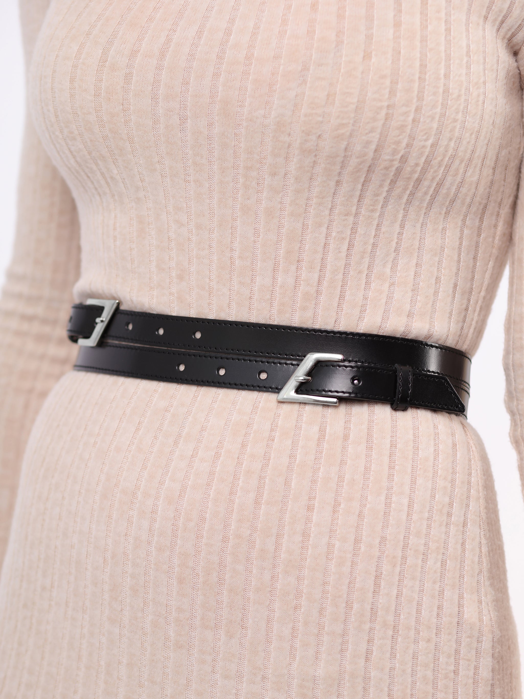 Detailed view of black leather double buckle belt.