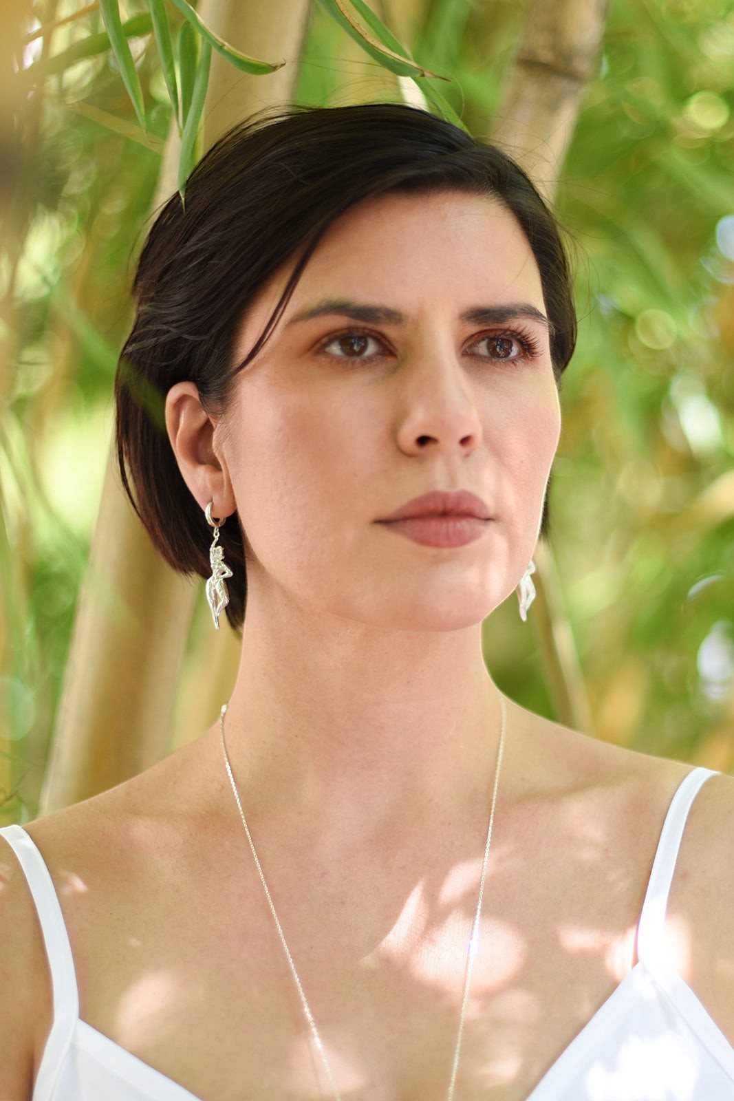 Ce Fain! Aethera sterling silver goddess huggie earrings worn by a woman with a matching silver necklace.