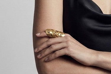 A model wearing a Ce Fain! handcrafted solid brass Hyperborean ring with intricate engraved symbols on her finger.