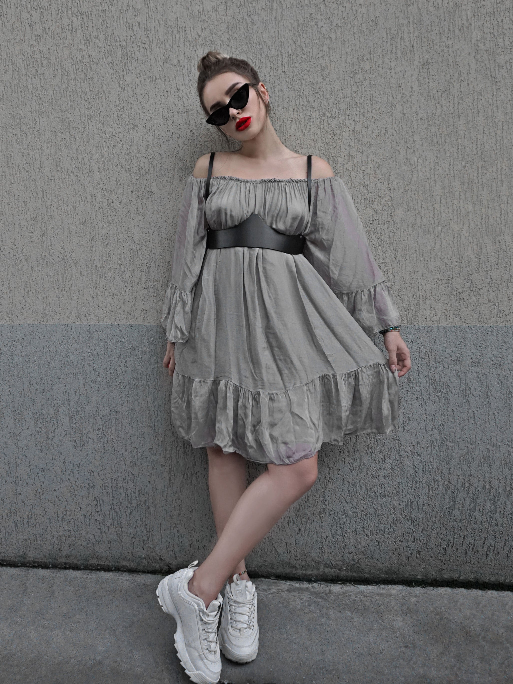 Black leather underbust harness worn with gray dress and white sneakers. 