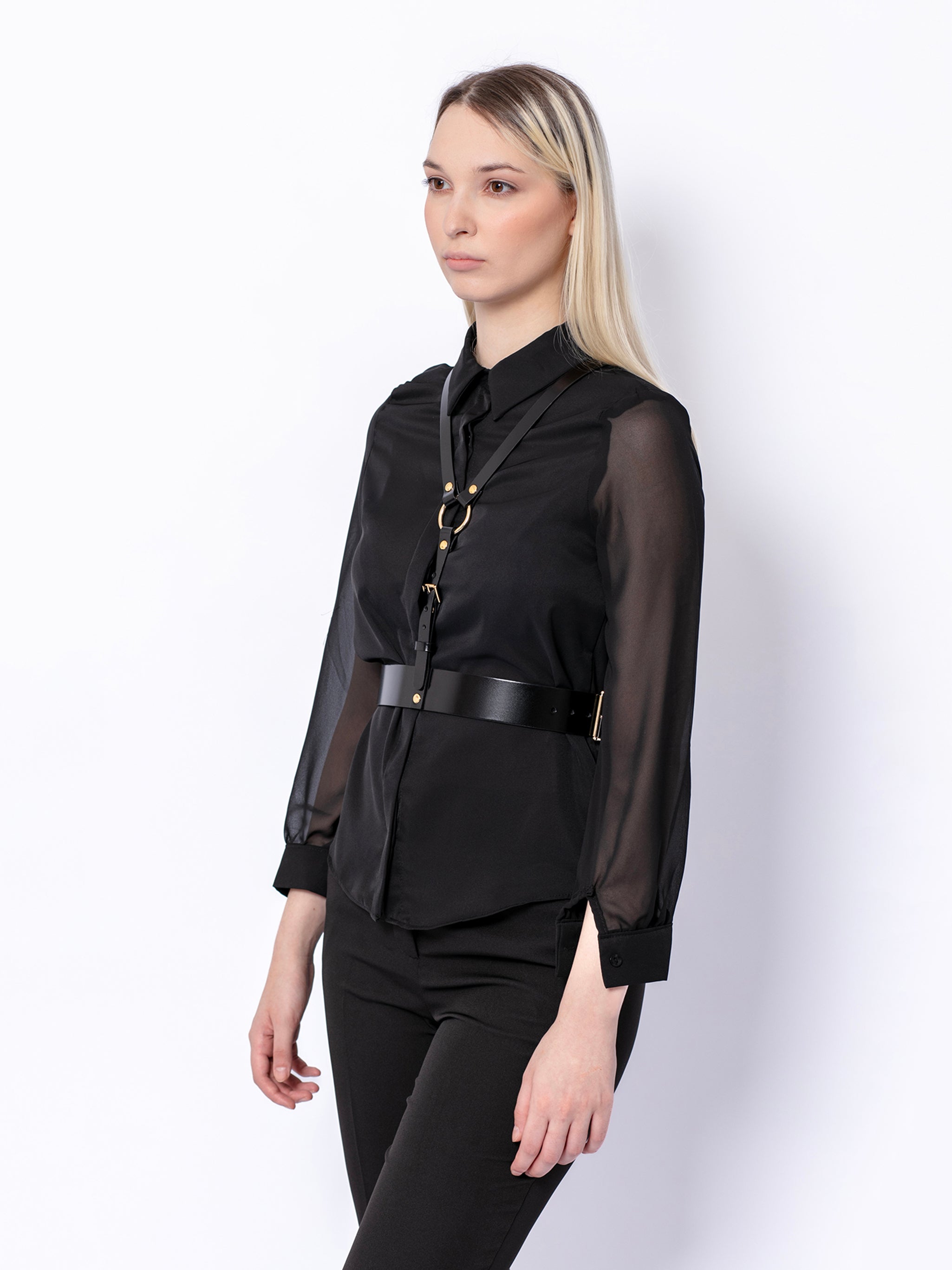 Side view of black leather harness worn by model over black shirt.